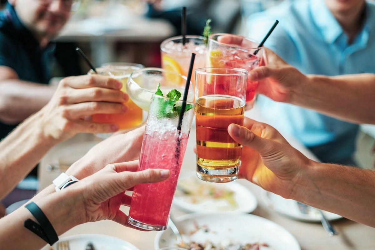 group of people with different alcoholic drinks clinking glasses